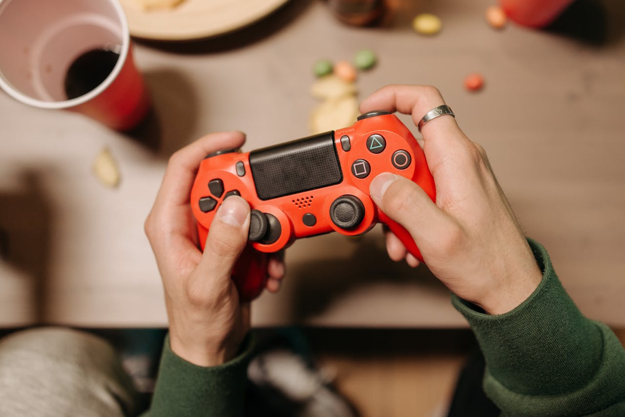 about-01 Person playing video games with a red controller at a desk.